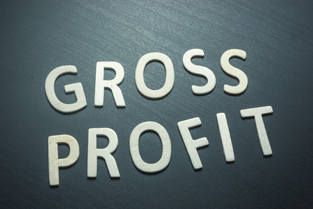 Gross profit written with wooden letters on a green background to understand a concept of economics and financeの写真素材