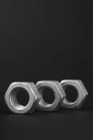 Three bolts on a black background to mean an industrial conceptの写真素材