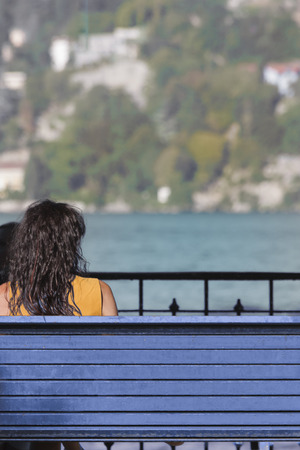 Woman sitting on a bench watching the sea to mean any conceptual topicの写真素材