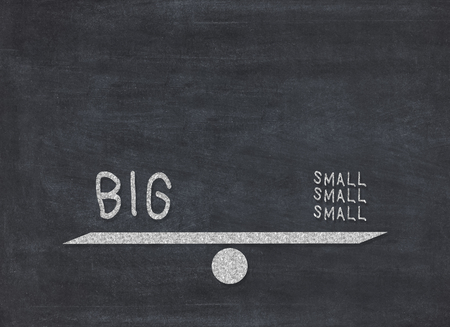 Big and small - seesaw weight balance concept on blackboard background to mean a business conceptの写真素材