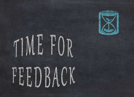 Time for feedback - Hourglass with text on a black background to mean a conceptの写真素材