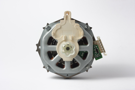 Fragment of the alternating current motor for household appliances with pulley for belt drive on a white backgroundの写真素材