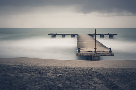 Sandy sea beach with old ruin wood pier in long exposureの写真素材