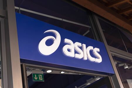 Valdichiana Outlet Village, Italy 09/17/2019: Closeup of the Asics lettering and logo on its facade to mean a business conceptのeditorial素材
