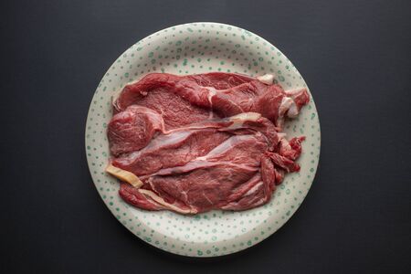 Raw meat on a black background semi-finished product for the kitchen the protein chef cutの写真素材
