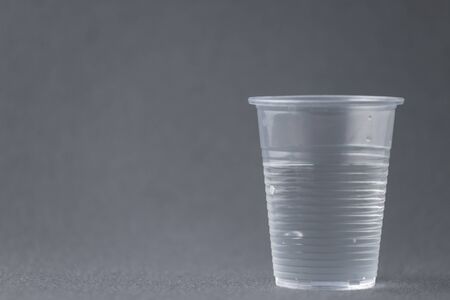 Plastic drinking glass filled with water isolated on gray background to mean a conceptの写真素材