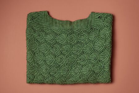 Green wool sweater on an orange background to mean a concept