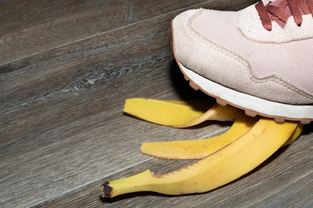 Foot crushing a banana peel on a wooden floorの写真素材
