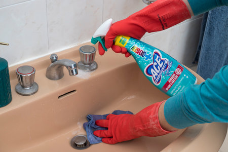 A person cleaning the bathroom sink with a glove with ACE BLEACHのeditorial素材