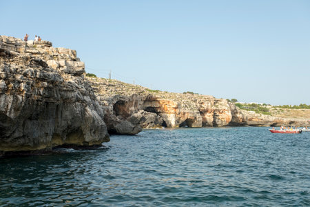 Coastal bay at sunset with boat, cliffs, and scenic rock formations.の写真素材