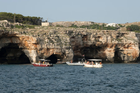 Coastal bay at sunset with boat, cliffs, and scenic rock formations.のeditorial素材