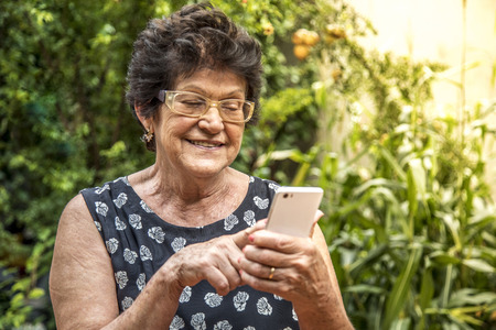 Happy elderly woman using cellphoneの写真素材