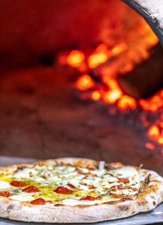 Delicious pizza being roasted in traditional wood ovenの写真素材