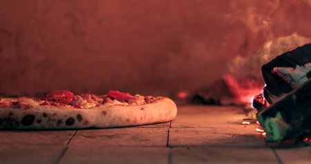 Delicious pizza being roasted in traditional wood ovenの写真素材