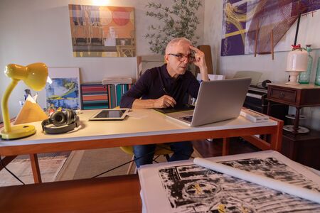 Middle aged man using computer in his art studio and drawing on his tabletの写真素材