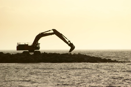 Excavator in backlight near the coastの写真素材