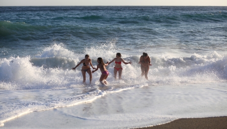 Four young girls in bikinis enjoy the spraying mediterranean wavesのeditorial素材