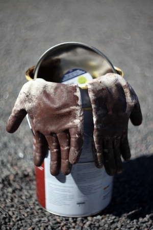 Two used working gloves hanging on empty paint bucketの写真素材