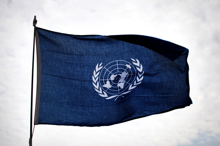The flag of the United Nation waving in the wind against the skyのeditorial素材