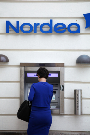 Blue dressed woman make a withdravel from Nordea cash pointのeditorial素材