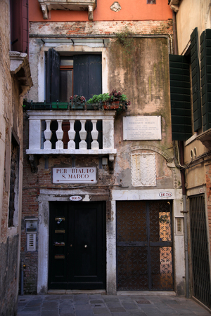 Narrow path between houses and buildings in Venice. With directions to san Marco and Rialto, Italyの写真素材