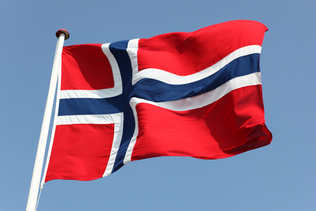 Norway's Flag on flagpole against blue sky.の写真素材