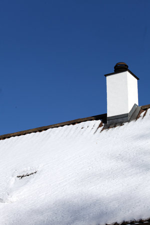 White chimney and roof with snow. A cold winter and possible lack of fuel and firewoodの写真素材