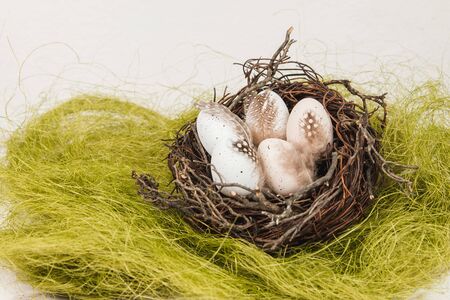 Pastel eggs in a bird's nest on a grass surfaceの写真素材