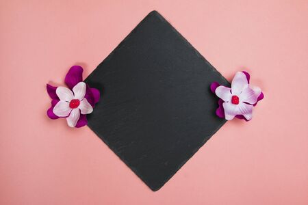 Black square with purple and white flowers on a pastel pink backgroundの写真素材