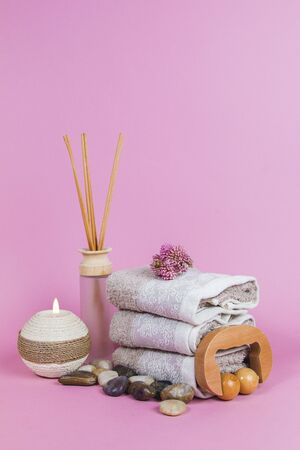 Spa essentials, aroma sticks, stones, towels and a plant on a pink backgroundの写真素材