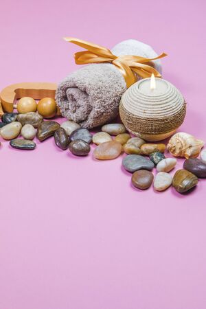 Spa essentials, aroma sticks, stones, towels and a plant on a pink backgroundの写真素材
