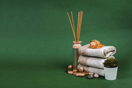 Spa essentials, candle, stones, towel and flowers on a dark green backgroundの写真素材
