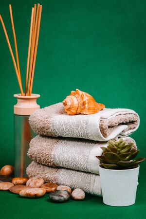 Spa essentials, candle, stones, towel and flowers on a dark green backgroundの写真素材