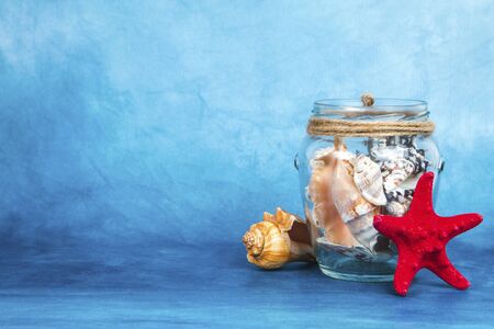 Jar full of seashells with the starfish on a blue backgroundの写真素材