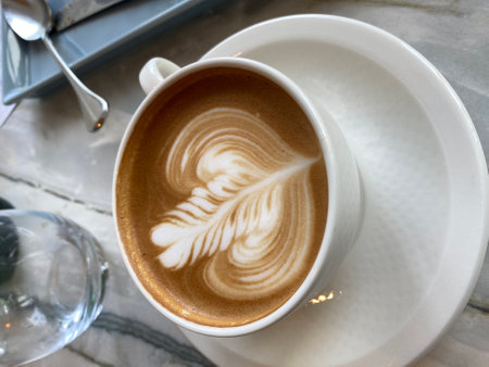 Hot latte art coffee in white cup on table in coffee shopの写真素材