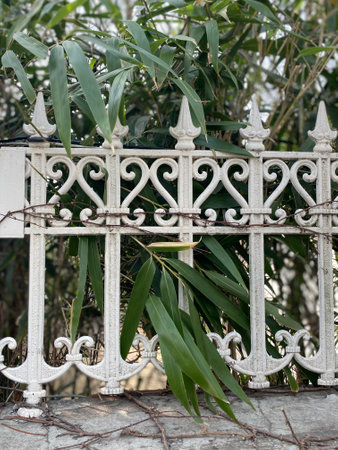 Decorative white metal fence on the street in the city park.