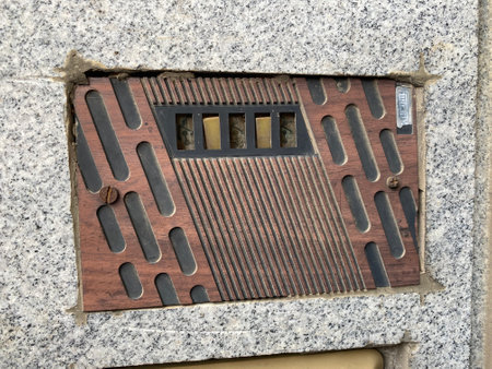 Close-up view of a ventilation grate on a concrete wall.