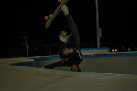 Skateboarder performing tricks in a skate park at night.