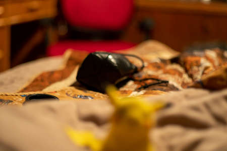 A closeup shot of a black mask lying on a bed in the bedroomの写真素材