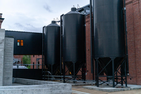 Modern black metal tanks for wine and beer on a background of red brick wall