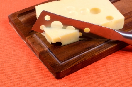 Cheese with a knife on a wooden boardの写真素材