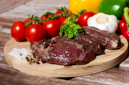 meat with fresh vegetables on wooden boardの写真素材