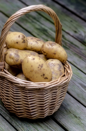 potatoes in basket on wooden floorの写真素材