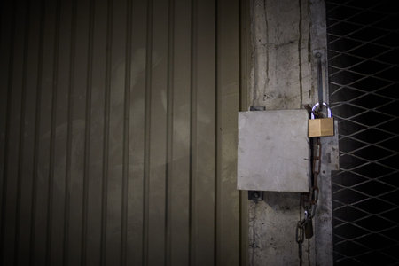 Close-up of a locked door, garage with fence. Idea of cage, prison, confinement, lockdown. Scary, gloomy and creepy atmosphere.の写真素材