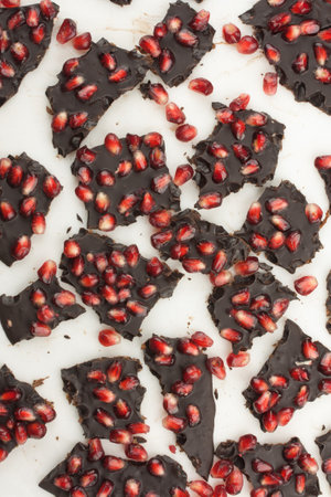 Dark chocolate with pomegranate seeds, chopped on white background, healthy sweets, background, flat layの写真素材