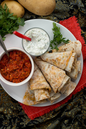 Aloo paratha flatbread served rolled up in cones with raita and hot pepper chutney, Indian potato stuffed bread, Close upの写真素材