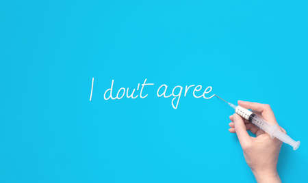 Hand holding syringe as a pen, signing agreement. Minimal anti vaccine concept.の写真素材