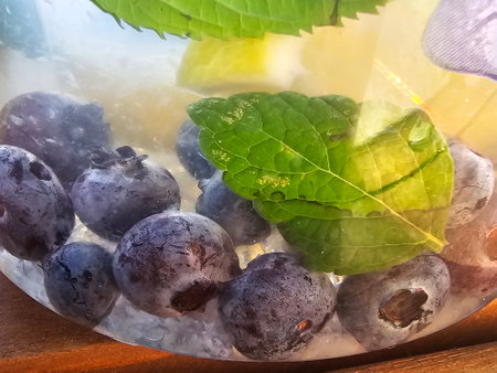 Blueberries and mint in ice cubes on a wooden table. Close up.の写真素材