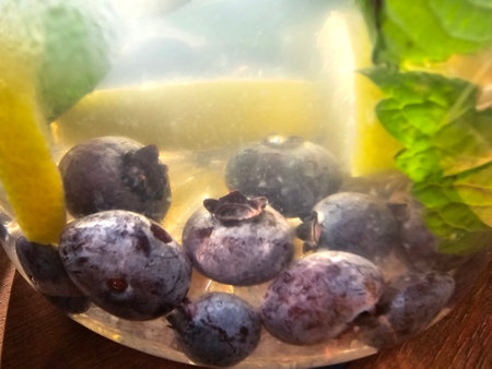 Blueberry, lemon and mint in ice cube on wooden table.の写真素材