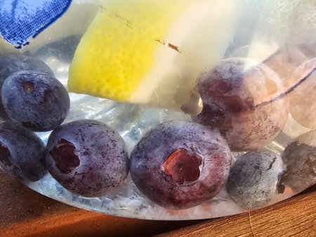 Blueberries in ice cubes with lemon and ice on wooden table.の写真素材